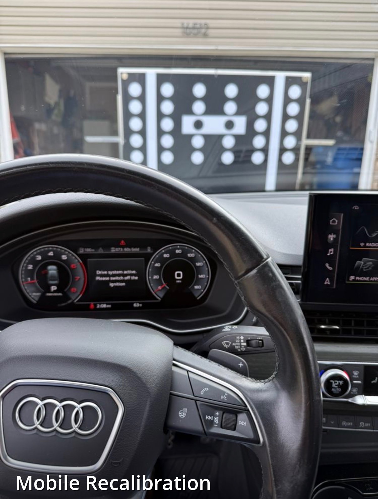 Calibration target board set up in front of a vehicle's windshield during a mobile ADAS recalibration